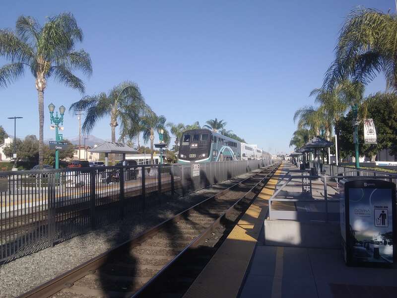 Metrolink station in Covina from the east end of the platform looking west. A train is arriving headed east towards Downtown LA.
