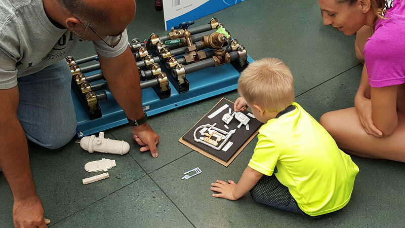 A little boy and his mom work with NRC Region III Project Engineer Nick Shah to identify parts of a nuclear reactor and discuss safety-related systems at D.C. Cook’s annual assessment meeting. Agency inspectors brought interactive items to use as