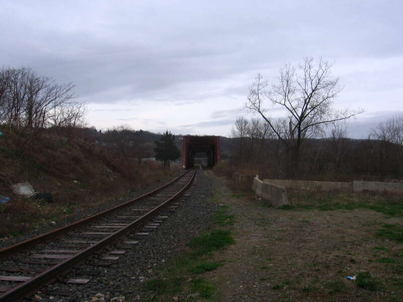 The Derby-Shelton rail bridge seen from East Canal Street in Shelton, Connecticut.  The second track has been removed.  The city of Derby is visible in the distance.