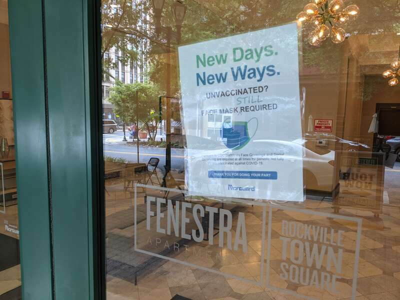 &quot;New Days. New Ways. Unvaccinated? Face Mask Still Required&quot; Fenestra Apartments, Rockville Town Square, Maryland.