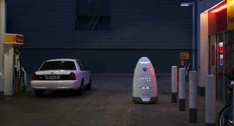 Knightscope K5 robot and a police car at a gas station in San Francisco in 2018.
