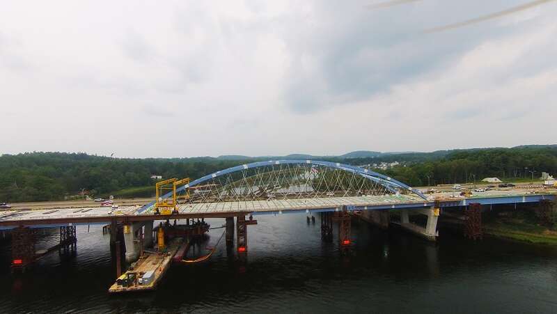 Construction of the new northbound span of the Whittier Bridge continues, as the concrete deck panels are installed and the hanger cables are prepped for stressing. In-water construction continues below the deck on the new and existing Whittier