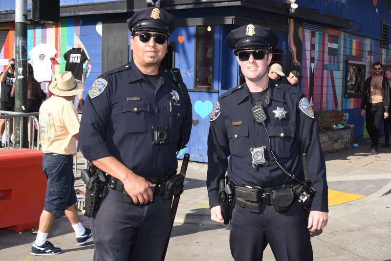 Officers R Davila and R Crockett of the San Francisco Police pose for a photo on Harrison Street at Ninth Street. Hearts appear playfully on the painted walls of a business behind them.

YDD_1813