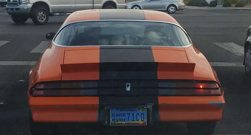 An orange second-generation Chevrolet Camaro Z28 with a black stripe stopped at the intersection of North Jones Boulevard and West Craig Road.