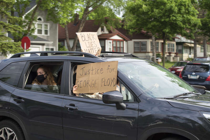 On May 26, 2020, people protested against police violence after the death of George Floyd. A dark SUV with protesters holding signs out the windows.