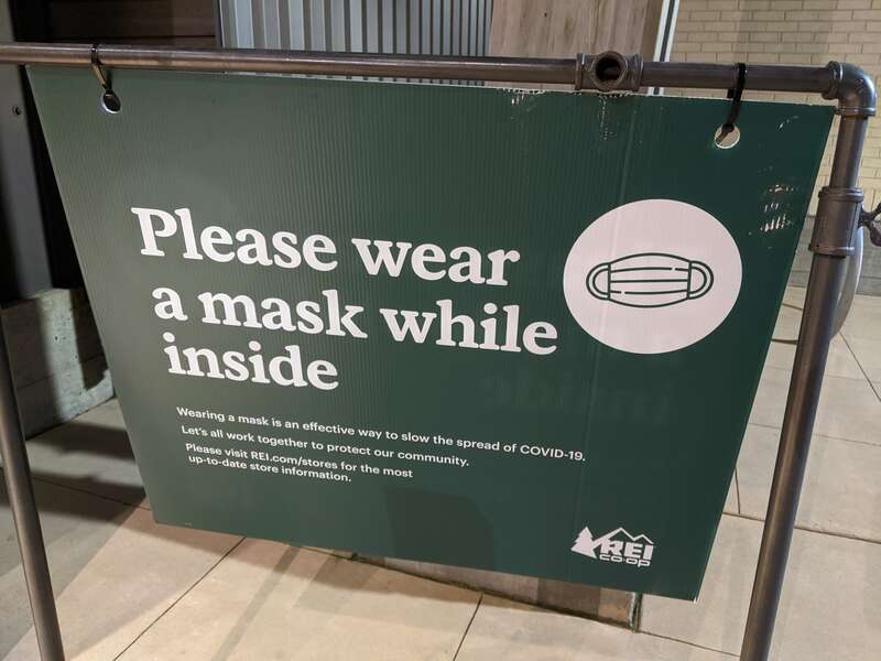 A sign at the entrance to REI Co-op: &quot;Please wear a mask while inside&quot;. 910 Rose Avenue, North Bethesda, Maryland 20852.
