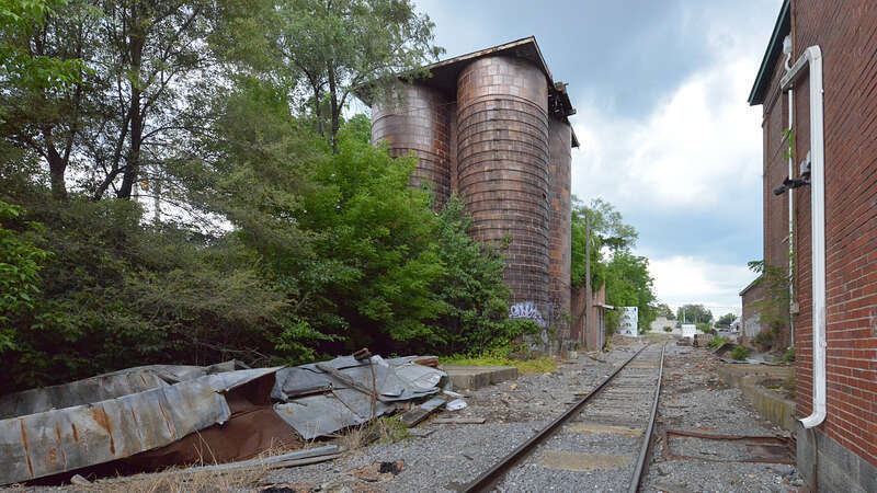 A cluster of four cylindrical glazed block grain silos used by the the Rockingham Milling Company. On the right is the side of the old mill. Cheaasapeake Avenue, just south of West Bruce Street, Harrisonburg, Virginia.