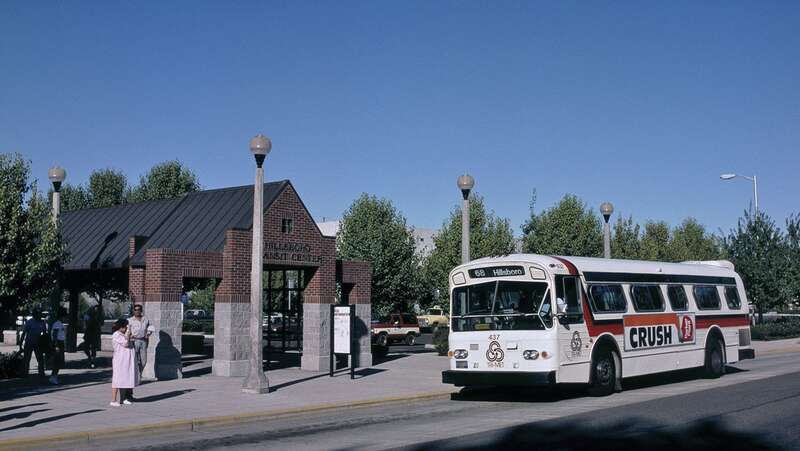 The south end, on Baseline Street, of the first Hillsboro Transit Center of Tri-Met (now TriMet), which was in use from 1988 to 1996 and also included a park-and-ride lot (visible in the background of this view).  Bus 437, a 1973 35-foot Flxible &quot;New