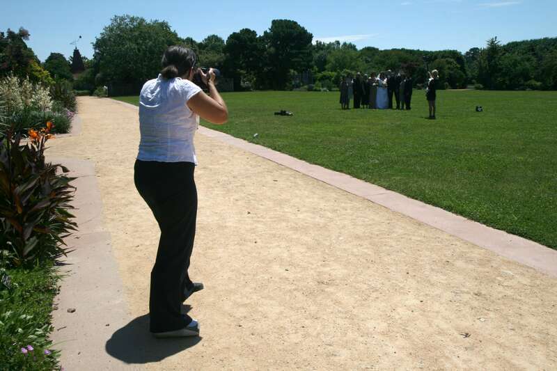 Photographer takes a group picture at a wedding held at the J. C. Raulston Arboretum in Raleigh, North Carolina.