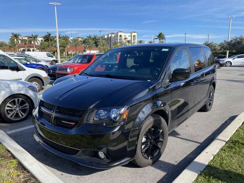 Front left side view of a 2017 Dodge Grand Caravan (RT) equipped with the GT package. A minivan finished in all black photographed in Florida. The 2017 Grand Caravan GT includes a unique performance suspension, distinctive monochromatic exterior,