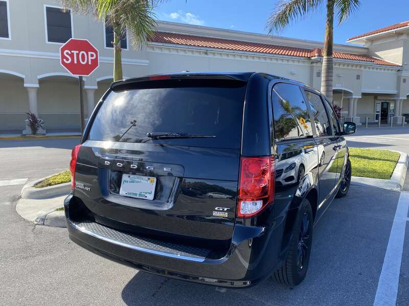Rear right side view of a 2017 Dodge Grand Caravan (RT) equipped with the GT package. A minivan finished in all black photographed in Florida. The 2017 Grand Caravan GT includes a unique performance suspension, distinctive monochromatic exterior,