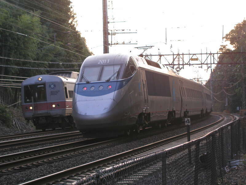 The trailing power car of a southbound Acela Express and the front of a northbound Metro-North railcar on the curve west of Riverside station in Greenwich, Connecticut