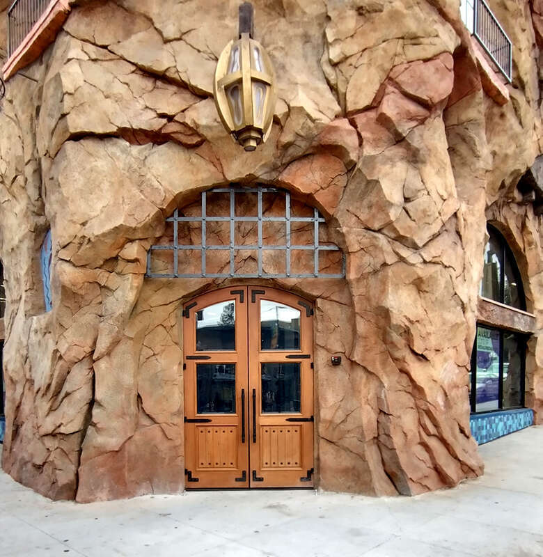 fake stone is plaster over metal wire,rebar, and metal stud frame.  Structural wall behind it is concrete