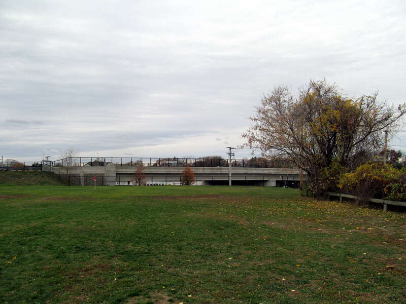 Site of the former Dedham station, closed in 1967. The station building was located in the far center of the shot just before the overpass; the grassy area (now a sports field) was once a rail yard.