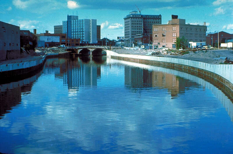 The Flint River in Flint, Michigan, USA, in the late 1970s during a U.S. Army Corps of Engineers flood control project, Taken from approximately halfway between the Grand Traverse Street bridge and Beach-Garland Street bridge, looking east. To the