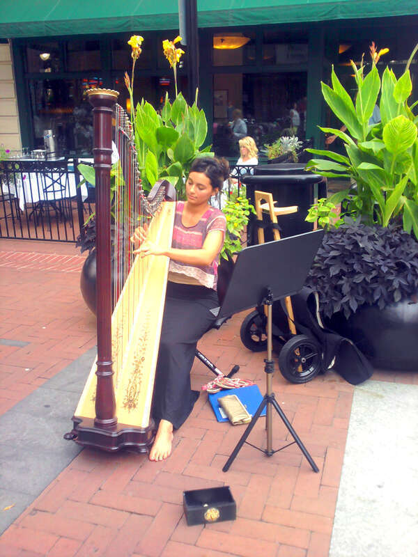 Young woman plays harp on Downtown Mall in Charlottesville, Virginia.