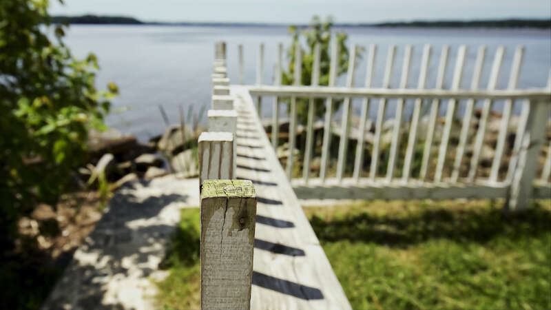 500px provided description: Fence in front of the Jones Point Lihthouse [#park ,#water ,#tree ,#summer ,#fence ,#green ,#shadows ,#perspective ,#footpath ,#light house ,#algae ,#boardwalk ,#fence posts]