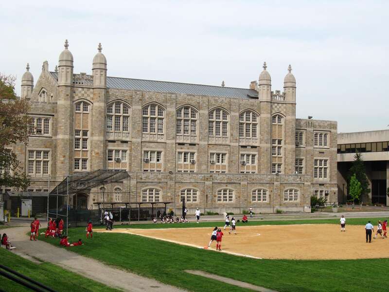 Looking northeast at girl baseball game and Old Gymnasium of Lehman College, Bronx, on a cloudy afternoon in spring.