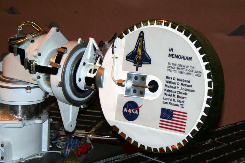 A memorial plaque mounted on the back of the high gain antenna on the Mars rover Spirit. The landing site of the rover was named Columbia Memorial Station in honor of the astronauts on the final mission of the Space Shuttle Columbia.  Image from
