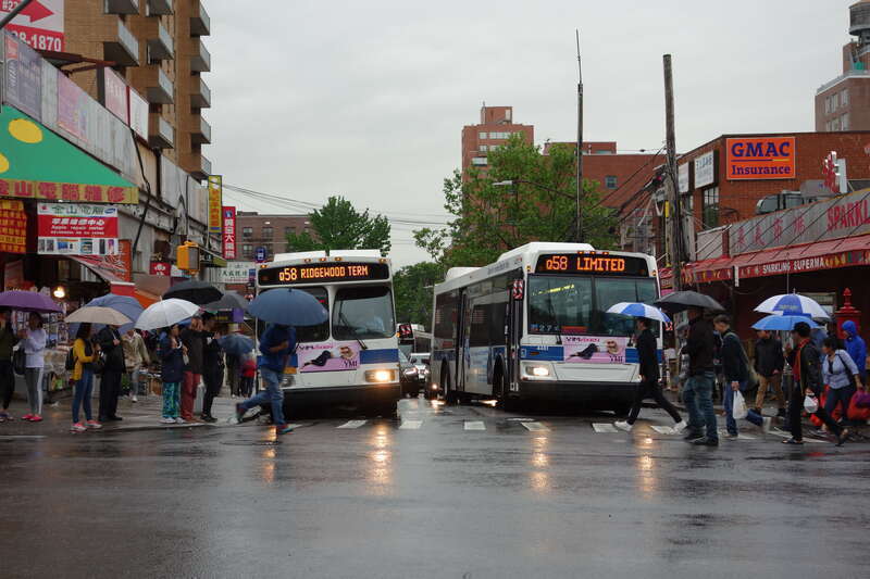 Pedestrians crossing in front of two Q58 buses at the route's terminus at Main Street and 41st Road in Downtown Flushing, Queens.