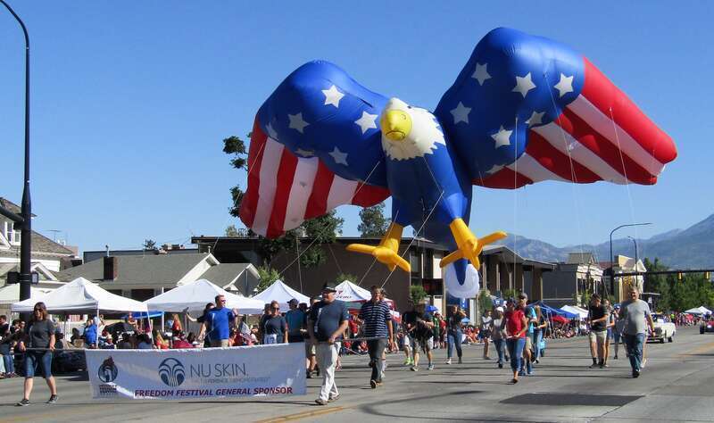 Marchers in the Freedom Festival Grand Parade with a Nu Skin banner and giant eagle balloon.