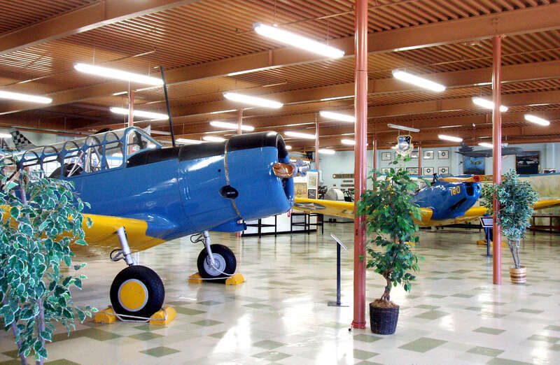 Travis AFB Museum interior with BT-13A in foreground and PT-19 in background.