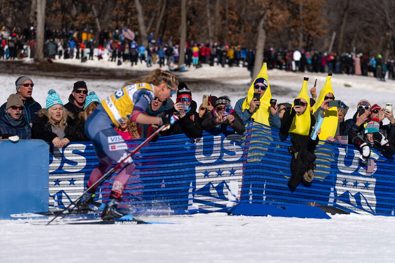 Jessie Diggins skis in the 10-kilometer race, passing three people in banana costumes, at the Loppet Cup at Theodore Wirth Park in Minneapolis, Minnesota, USA.