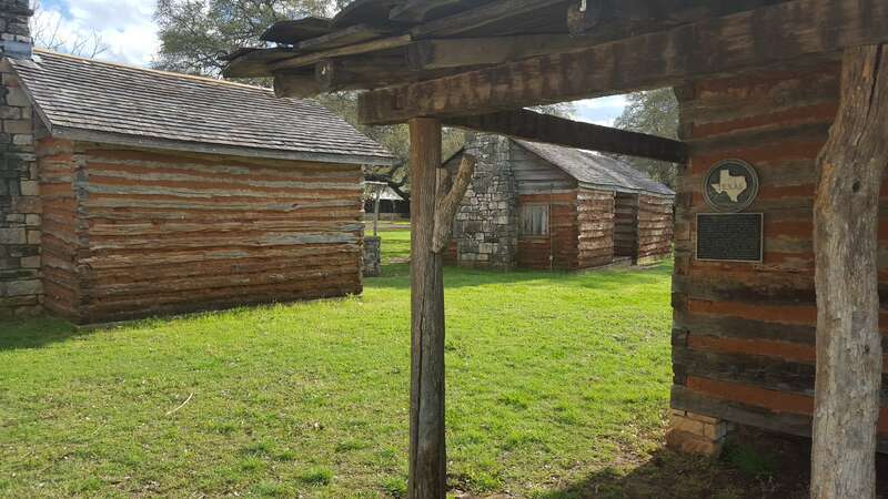 View of three of the historical log cabins on the grounds of the Old Settlers Association, Georgetown, Texas. The cabins of squared logs and hand-hewn limestone were built in the early 1850s near the village of Gabriel Mills, Texas. They stood on