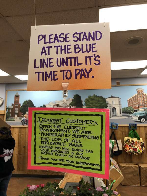 Sign at checkout area at Trader Joe's in North Bethesda, Maryland asking customers to keep their distance and to inform them of the bagging policy.