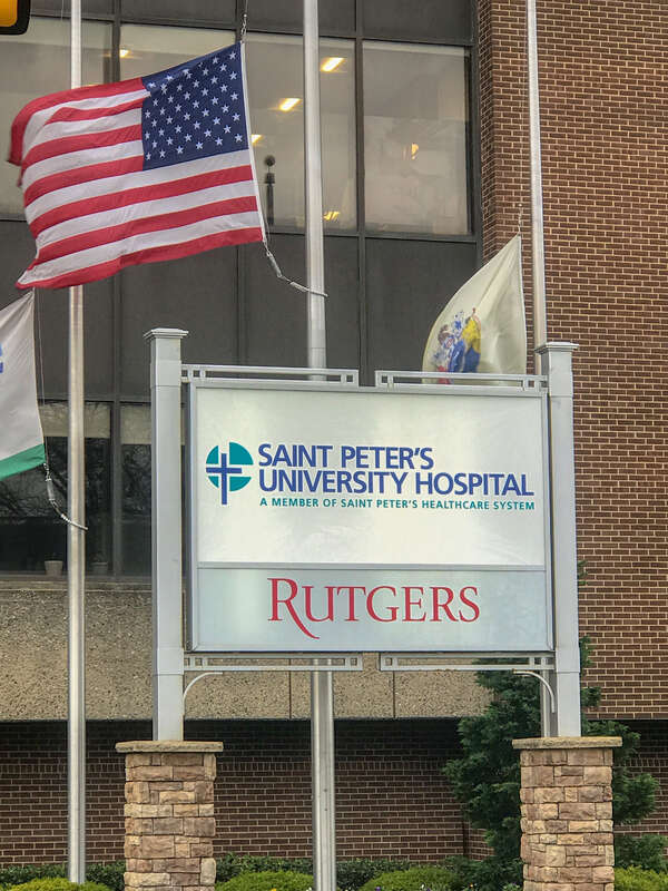 Sign with flags above the main entrance to Saint Peters University Hospital
