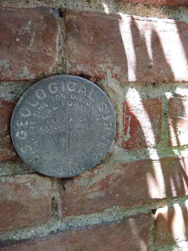 This is a picture from the side of an early USGS California vertical control marker disk, apart of the SF (San Francisco) datum, located on the east side of the old Gilroy, California city hall. The marker was placed in 1908.