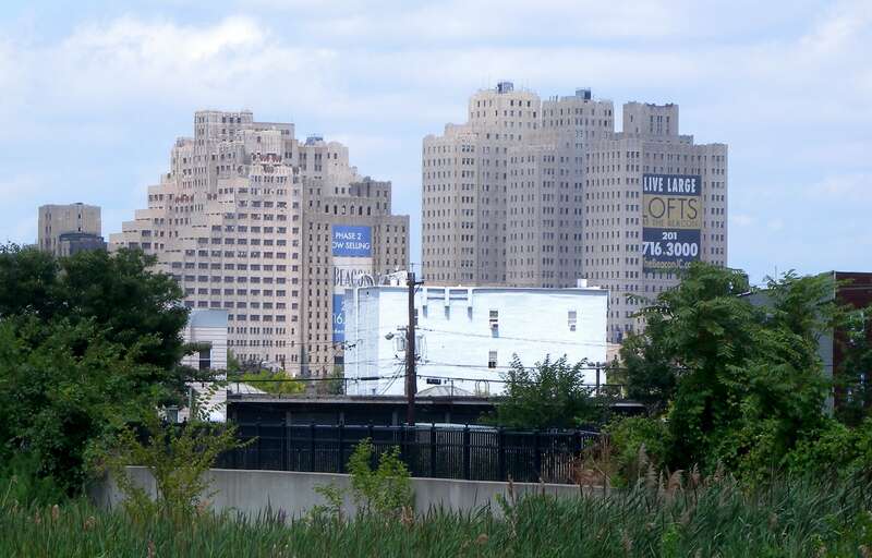 Looking northwest from parking lot of HBLR station of Liberty State Park, west at the former Jersey City Medical Center on a partly cloudy midday.  See also File:JCMC old fr SI Ferry jeh.jpg.