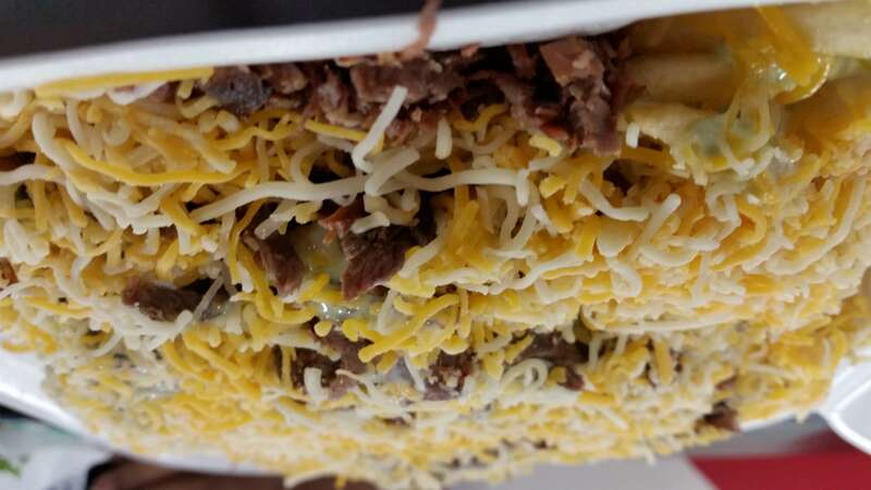 A close up shot of a bisected full size order of Carne Asada Fries made at  Tacos El Gordo on Broadway in Chula Vista, California