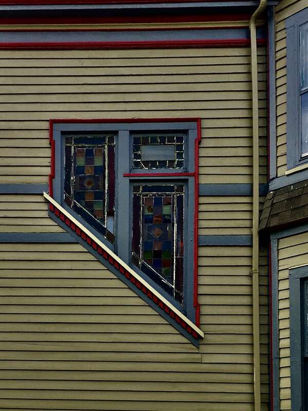 Decorating the east side exterior wall of the house at 148 York Street on the West Side of Buffalo, New York is this odd-shaped stained-glass window, featuring simple geometric tracery and an interesting raking dental low along its slanted lower