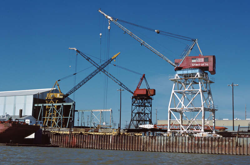 Looking NW from river toward Jeffboat shipyard.
&quot;Spirit of 76&quot; and other whirler (or whirley) cranes are used to hoist and move large steel pieces for boat and barge construction. The cranes, which can rotate 360 degrees, are mounted on frames which