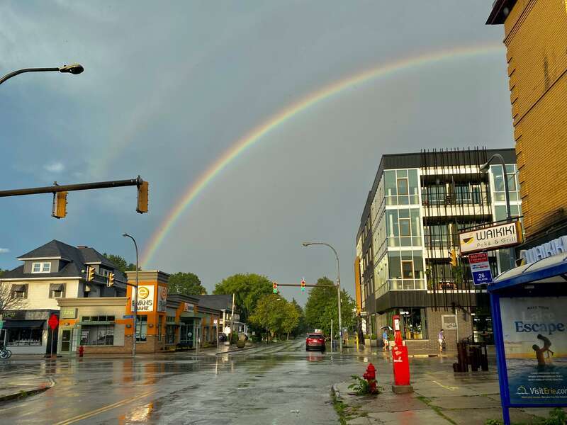 A bright rainbow hangs in the sky over the corner of Elmwood and West Delavan Avenues in Buffalo, New York at the end of a brief but heavy downpour on an August 2022 evening.