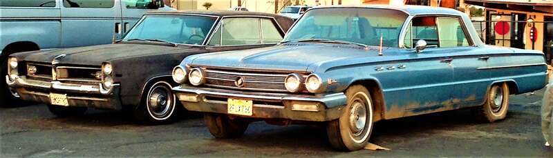 Two Old cars pose for a picture together