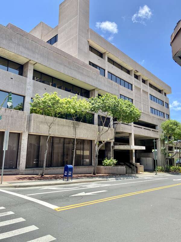 Built in 1960, this Brutalist building was constructed as the headquarters of the Hawaii National Bank.  The building features a rough textured concrete exterior, boxy geometric forms, a protruding parapet on the exterior facing walls, ribbon