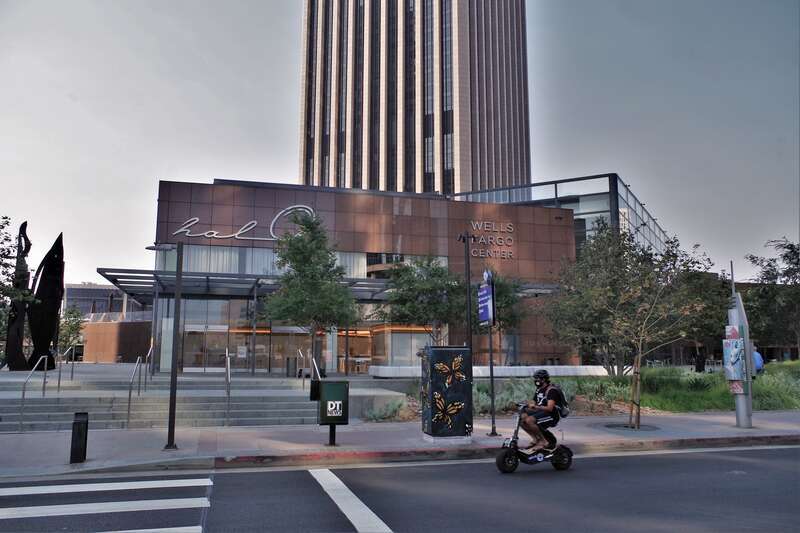 Young man cruises on by on an empty Grand Ave. in the heart of Los Angeles. Soon to open is Halo a new burger / bar once this pandemic is over! Truly a Covid19 scene!