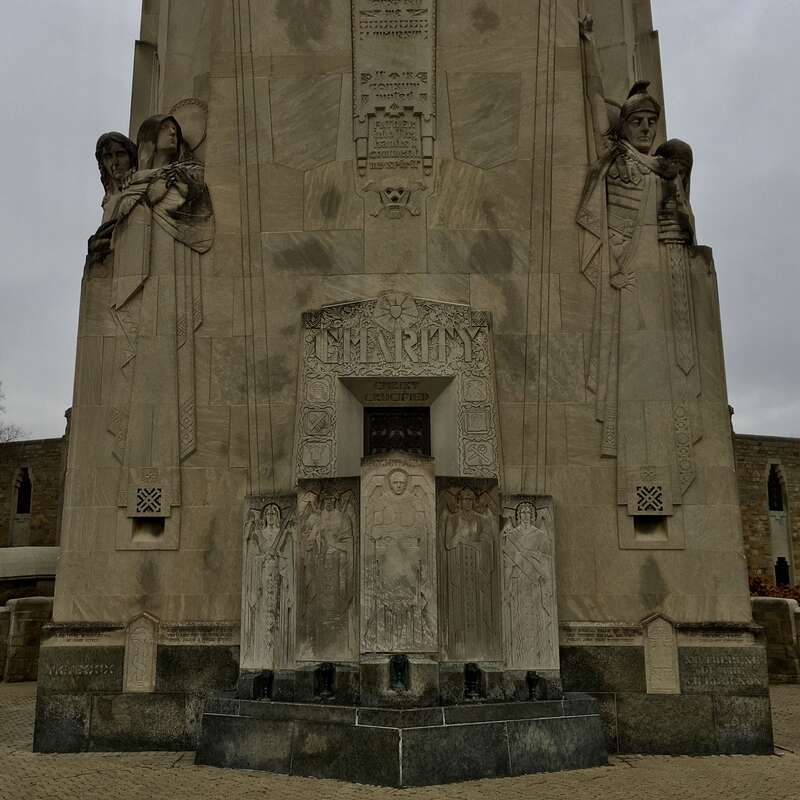 Stylized sculptures in high relief of John the Apostle and the Virgin Mary (left) and a Roman centurion holding the sword of Mary Magdalene (right), all sculpted by Rene Paul Chambellan, flank the outdoor pulpit at the base of the Charity Crucifixion