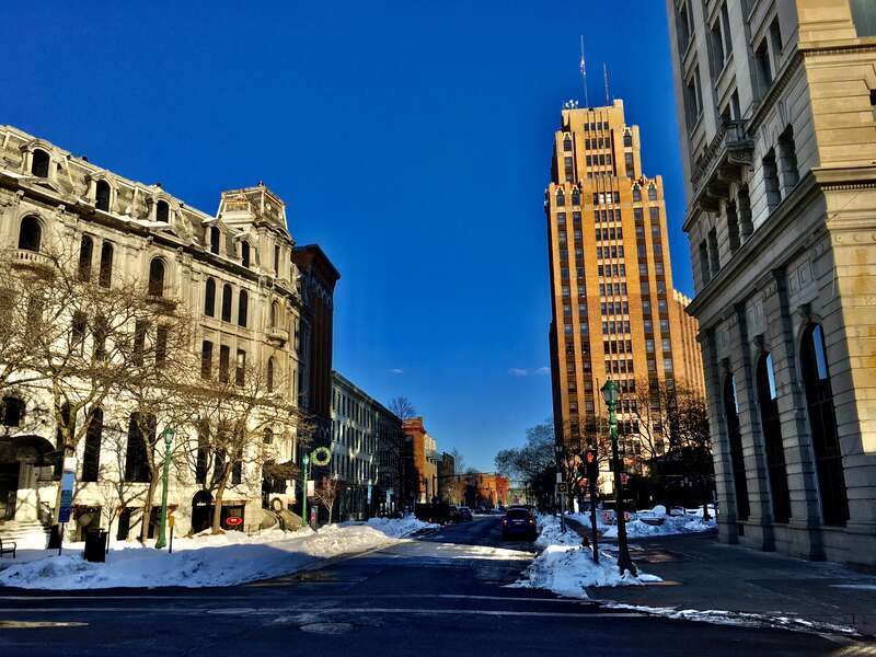 Looking eastward along East Water Street in downtown Syracuse, New York, from the southeast corner of Clinton Square on a frigid February 2021 evening. The Gridley Building (1867) and the Onondaga Savings Bank Building (1896) are seen at the left and