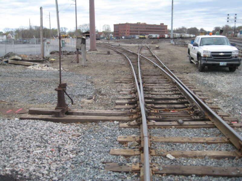 Picture inside the Lawrence yard's left (southeast) side looking at next old manual switch and mechanism a few more yards off the sidewalk from File:2014-0428-IMG 5171-Lawrence,MA Yd, Older switchstand, bent up vandalized target.JPG (short older