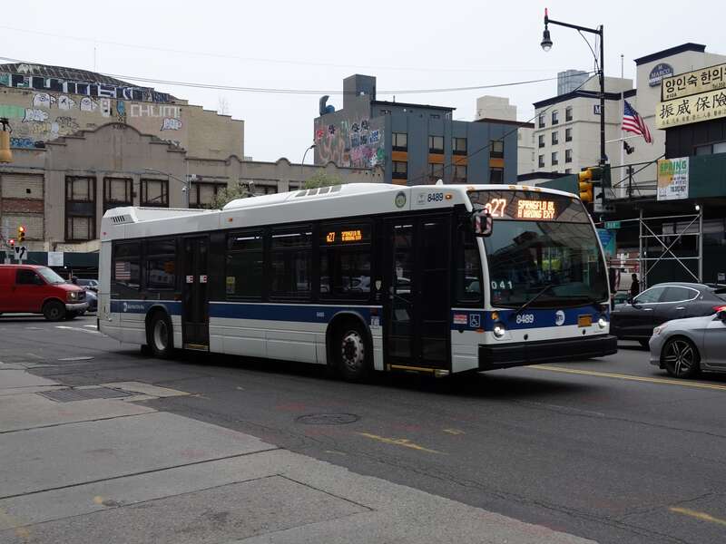 A Springfield Boulevard–Horace Harding Expressway (Oakland Gardens)-bound short run Q27 bus turning south from Northern Boulevard onto Main Street in Downtown Flushing, Queens. This bus has a Wi-Fi sticker indicated it has been retrofitted with