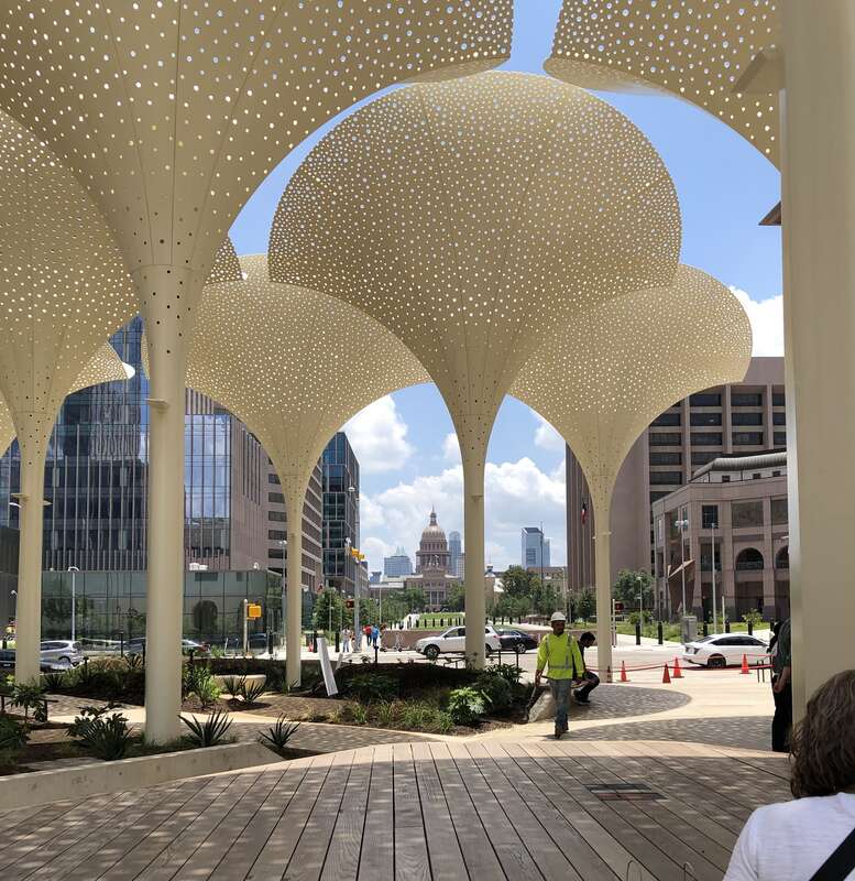 Exterior grounds and plaza designed by Snøhetta at the Blanton Museum of Art in Austin, Texas. Features include twelve towering, three-stories-tall &quot;petals&quot; which provide perforated shade. In the distance is the Texas State Capitol building. Photo by