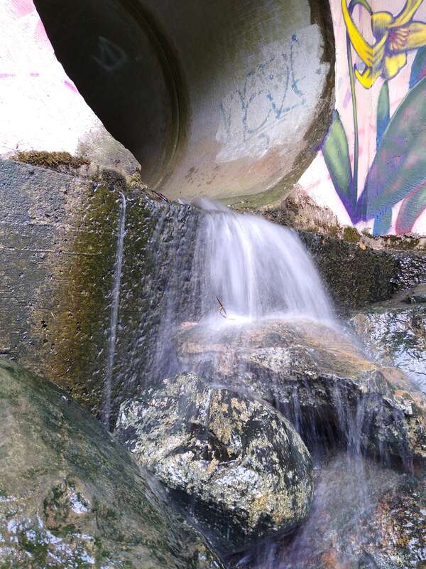 Water flowing out of a drainage pipe on a rainy day. Below the rocks in the picture, the water flows into Bolin Creek, near where the Bolin Creek Trail passes under Martin Luther King Jr Blvd in Chapel Hill, North Carolina.