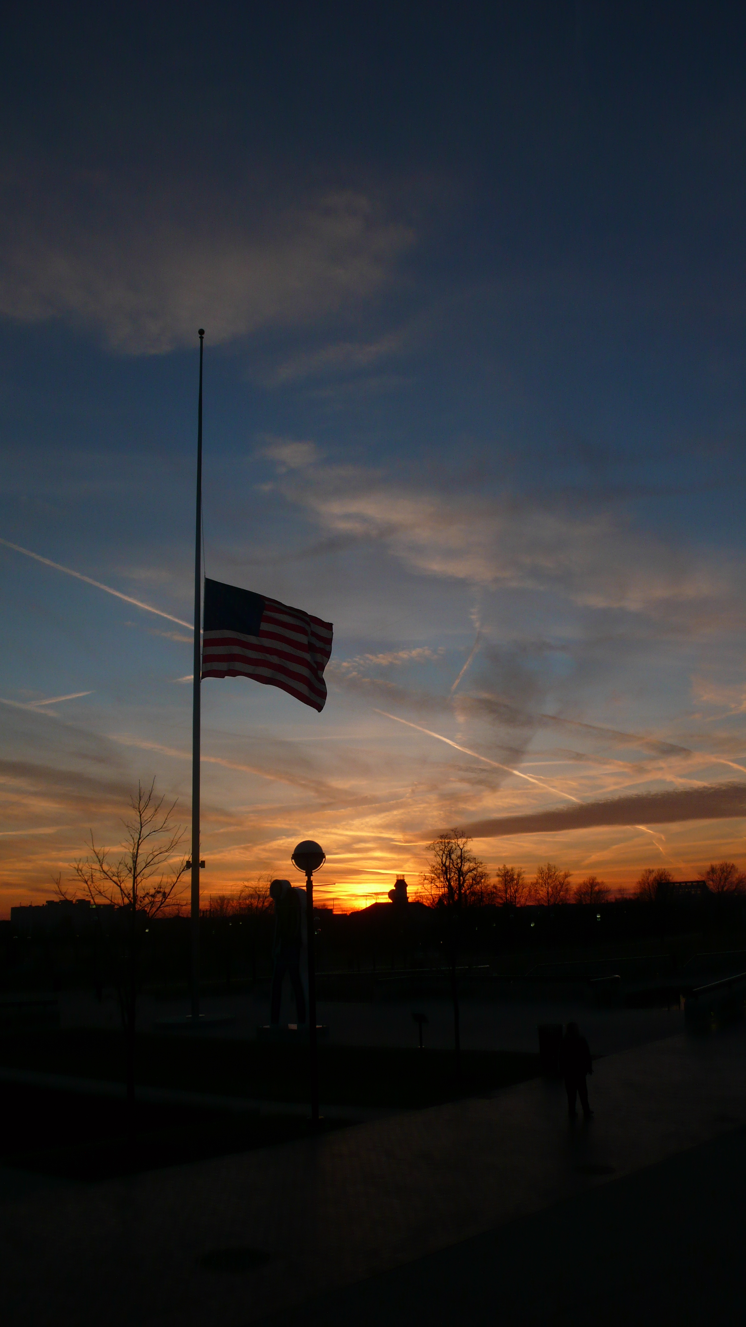 US flag flying at half-staff at sunset in White River State Park, Indianapolis, Indiana, United States.
