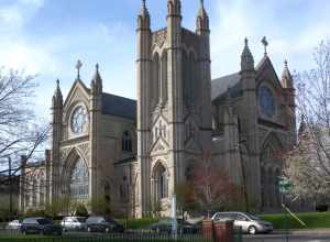 Looking north across Avenue C and 23d Street at Saint Henry Catholic Church on a sunny afternoon.
