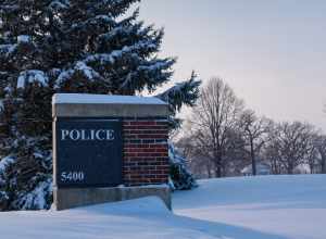 The entrance sign for the City of Brooklyn Park Police Department headquarters at 5400 85th Avenue North in Brooklyn Park, Minnesota, on a snowy afternoon.