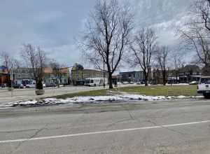 As seen in the historic Elmwood Village of Buffalo, New York on a March 2022 afternoon, an outbound NFTA Metro bus on route #20 crosses verdant Bidwell Parkway as it plies its prescribed northbound route along Elmwood Avenue. The bus will end its run