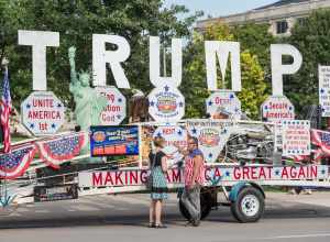 A reporter interviews Robert Cortis in front of his "Trump Unity Bridge" trailer at the University of Iowa campus in Iowa City, Iowa, on August 18, 2017.